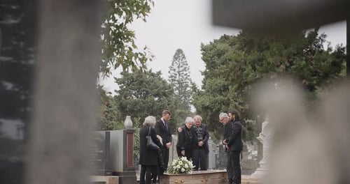 People at a funeral, death and graveyard with family mourning outdoor, grief and loss with coffin