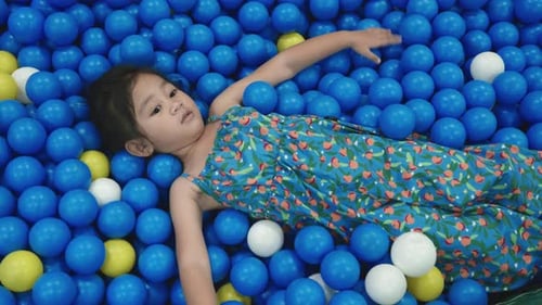 Happy Asian child woman having fun on entertainment center inflatable castle in balls sea