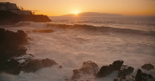 Raging Ocean Water Crash on Cliffs at Goden Sunset Light Stormy Sea Waves Splash at Rocky Coastline