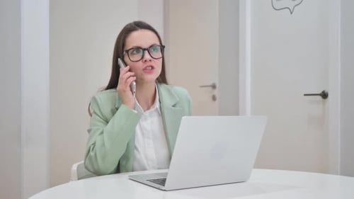 Woman in Office on Phone Call with Laptop