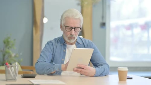 Senior Man Using Tablet at Office Desk