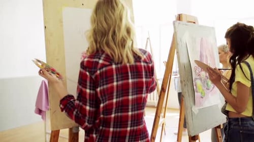 Art School, Creativity And People Concept - Group Of Students With Easels And Palettes Painting S...