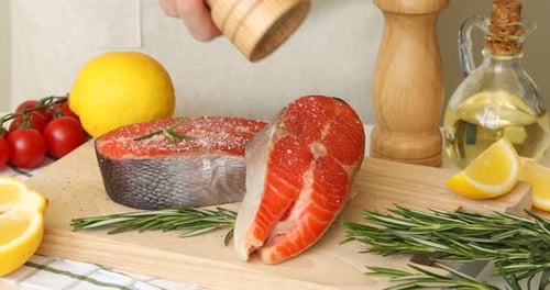 Raw salmon steaks seasoned with pepper on cutting board