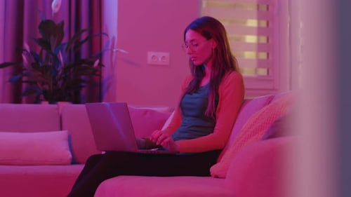 Woman Typing on Laptop on Couch at Home