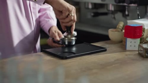 Nahaufnahme der Hände eines Barista beim Kaffeepressen mit einem Templer
