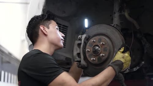Slow motion shot of a car mechanic checking the brakes and pads on a car