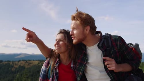 Cheerful Woman and Man Standing on Top of Mountain. Male Hiker Pointing