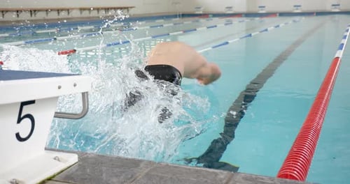 Splashing into swimming pool, swimmer making big splash during swim practice