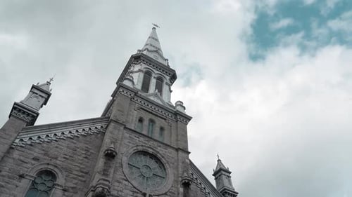 Slow motion film looking up at a beautiful church building with white clouds and blue sky overhead o