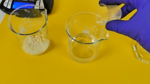 Technicien de laboratoire versant un ingrédient et remuant un mélange dans un bécher pour émulsion cosmétique
