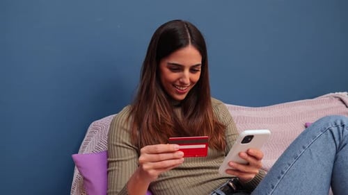 Woman using smartphone and credit card at home
