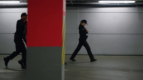 Man Escorted by Police Officers in Dark Garage