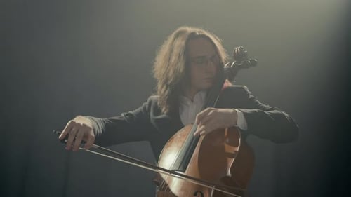Musician in Suit Playing Cello on Black Background