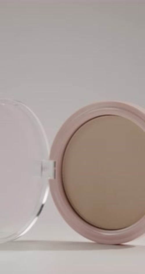 Poudre de maquillage rose compacte à fermeture lente sur fond blanc