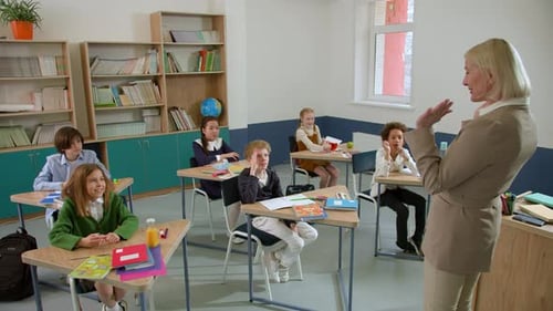 Elementary School Class Children Communicate with the Teacher Answering Question