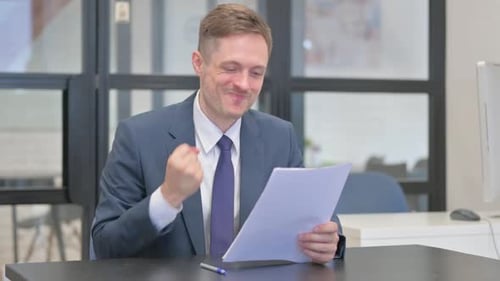 Man at Desk Celebrates Good News in Documents