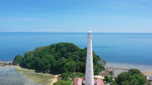 aérea do farol branco na remota ilha de Lengkuas com turistas na água azul tropical de Belitun