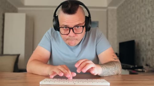 Man Using Keyboard With Headphones At Desk