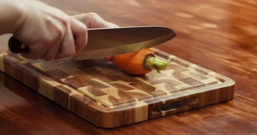 Close Up of Hands Cutting Fresh Carrot in Half with Knife on Wooden Table Preparing Ingredients for