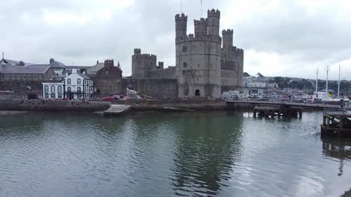 Ancient Caernarfon castle Welsh harbour town aerial view medieval waterfront landmark low left risin