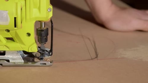 Close-up of electric jigsaw in action, men's hand cutting up wood board with a jigsaw in 4K