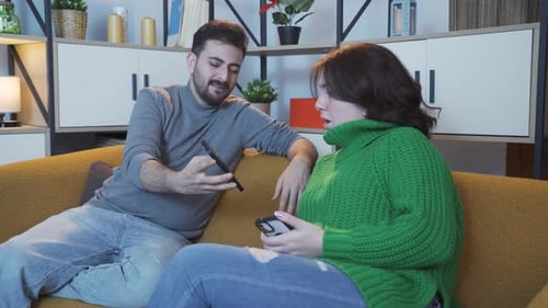 Couple Discussing Phone on Couch Indoors