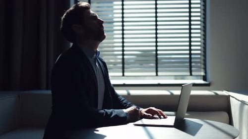 Adult Types on Laptop by Bright Window