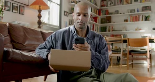 Man with Box Using Phone Indoors at Home