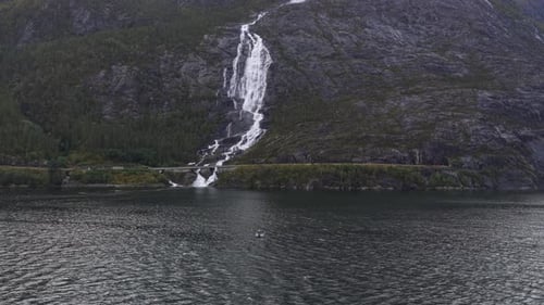 Aerial view of Langfossen waterfall and fishing boat in Norway fjord