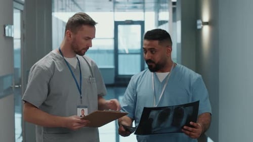 Doctors Walking Down Hospital Hallway Discussing X-Ray
