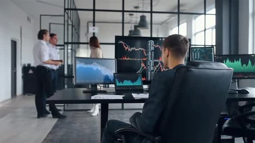 Excited man talks by phone. Team of stockbrokers works together in modern office at daytime