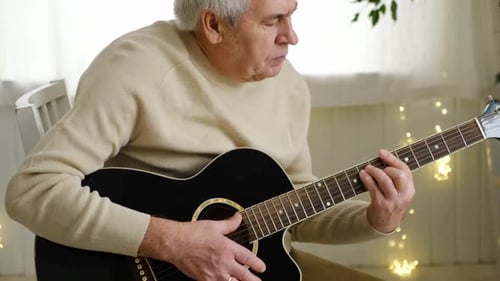 Senior Man Plays Acoustic Guitar at Home