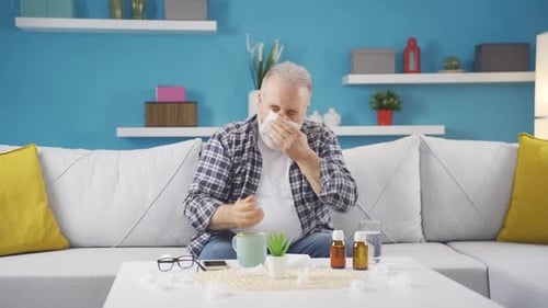 Man Drinks Tea and Uses Tissue in Living Room