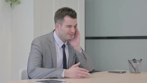 Man in Suit Rubbing Head in Office