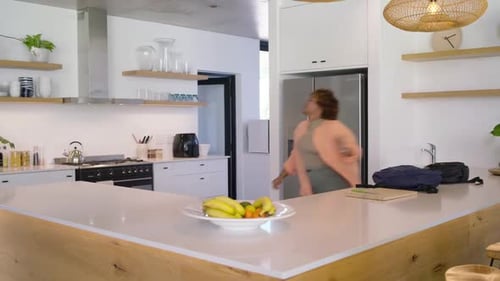 Femme afro-américaine déballant son sac à dos dans la cuisine, scannant la salle se dirigeant vers les escaliers, espace de copie