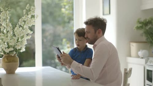 Father and Son Using Tablet in Kitchen