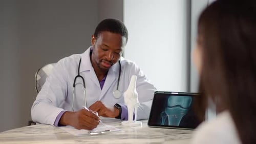 Doctor explaining knee x-ray to patient in office