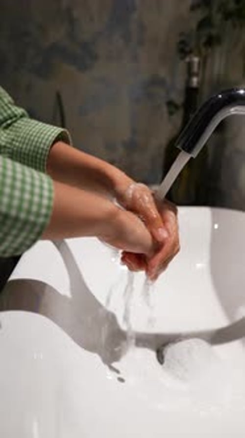 Hands Washing Under Running Water in Bathroom Sink