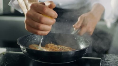 Chef Squeezing Lemon Juice onto Fish in Pan