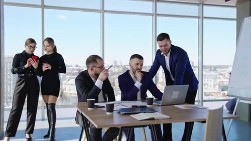 Men in office talking about work sitting at the desk with papers and laptop.