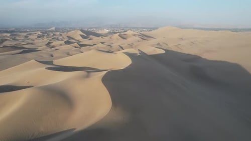 Aerial shot of desert sand dunes against sky, idyllic view of arid desert landscape - Huacachina, Pe