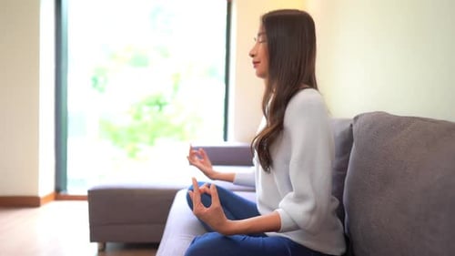 Woman Meditating Calmly on Couch in Bright Living Room