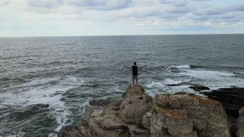 man standing rocks sea