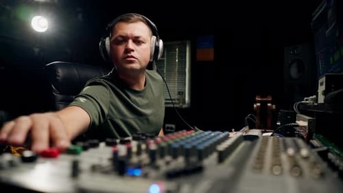 A close-up of a mixing console device used by a man working as professional sound engineer
