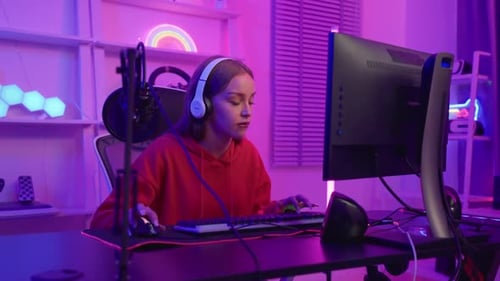 Woman Using Computer and Headphones in a Lit Room