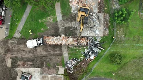 Construction site with excavator loading debris into a dump truck, aerial view