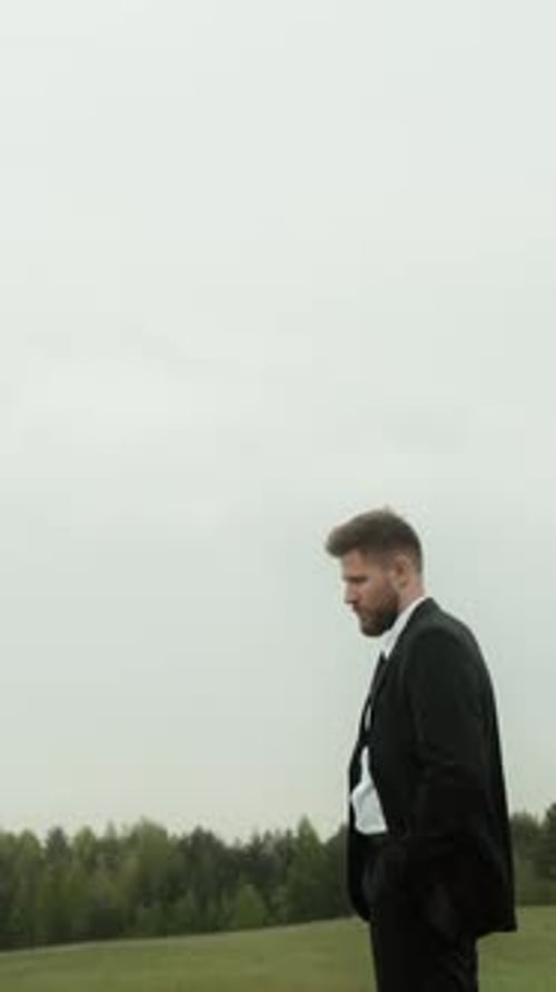 Man Stands Mourning by Coffin in a Rural Field