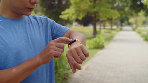 Sportsman Using Smartwatch during Morning Workout in Park