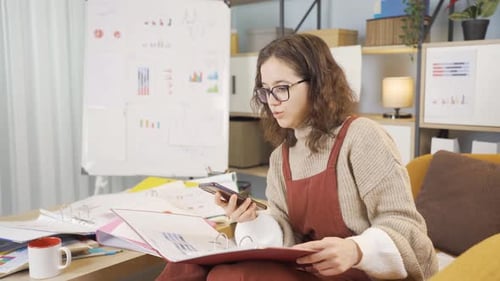 Young Woman Talking on Phone Reviewing Charts at Home