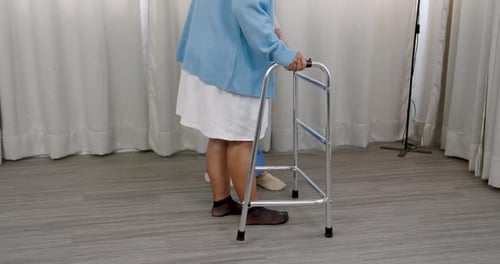 Woman uses walker with medical professional assistance
